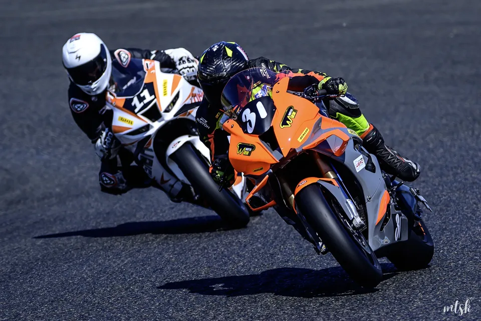Deux motos orange engagées côte à côte dans une courbe