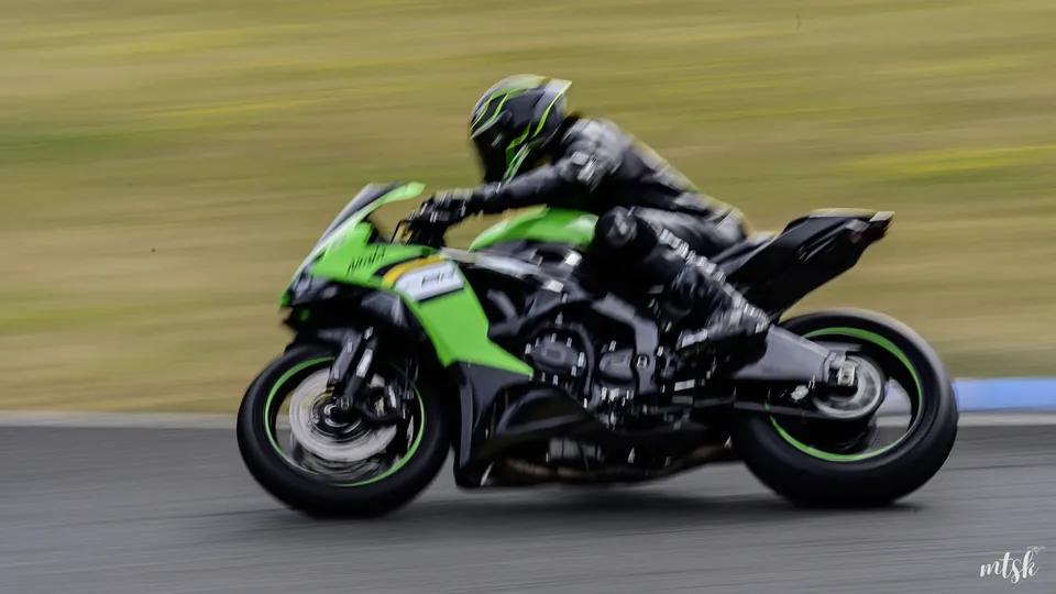 Filé latéral d’une moto verte à haute vitesse sur circuit