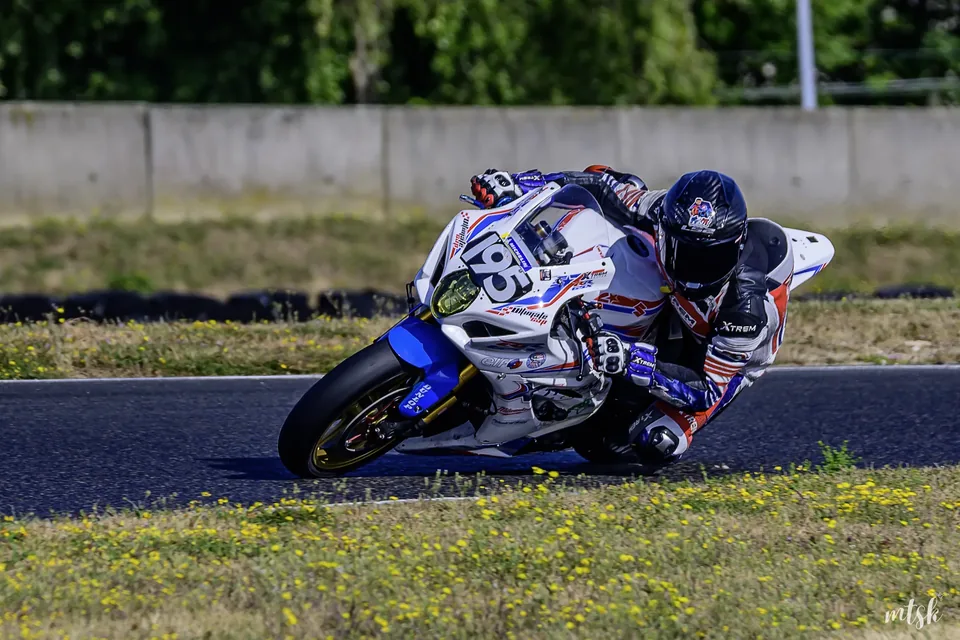Moto blanche et bleue inclinée au point de corde sur circuit