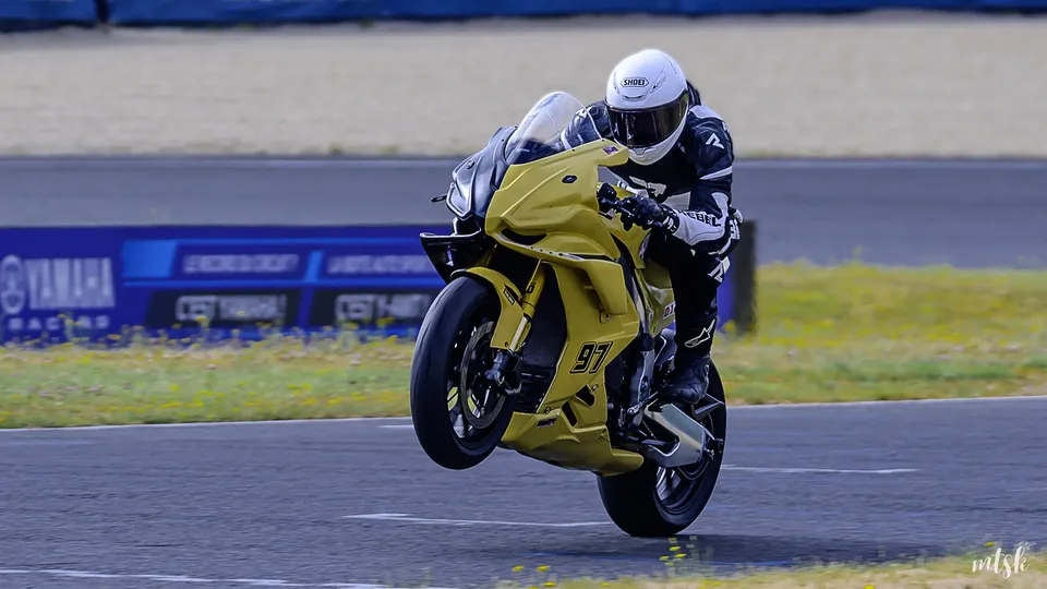 Moto jaune photographiée de face avec la roue avant légèrement délestée