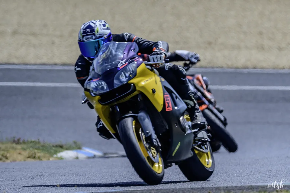 Moto noire et jaune photographiée de face à l’entrée d’un virage
