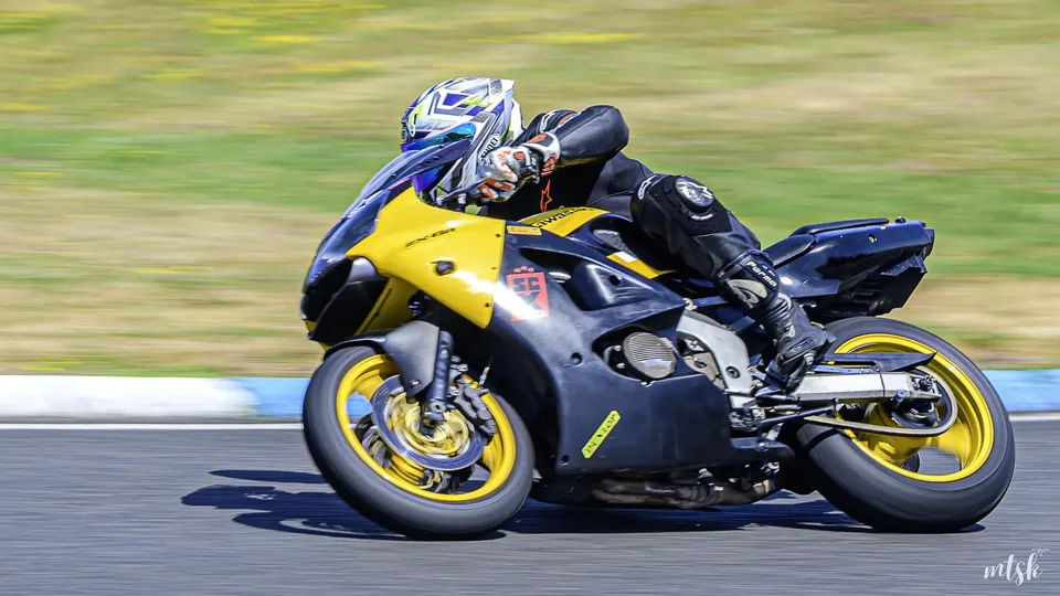 Moto noire et jaune suivie en mouvement dans une courbe