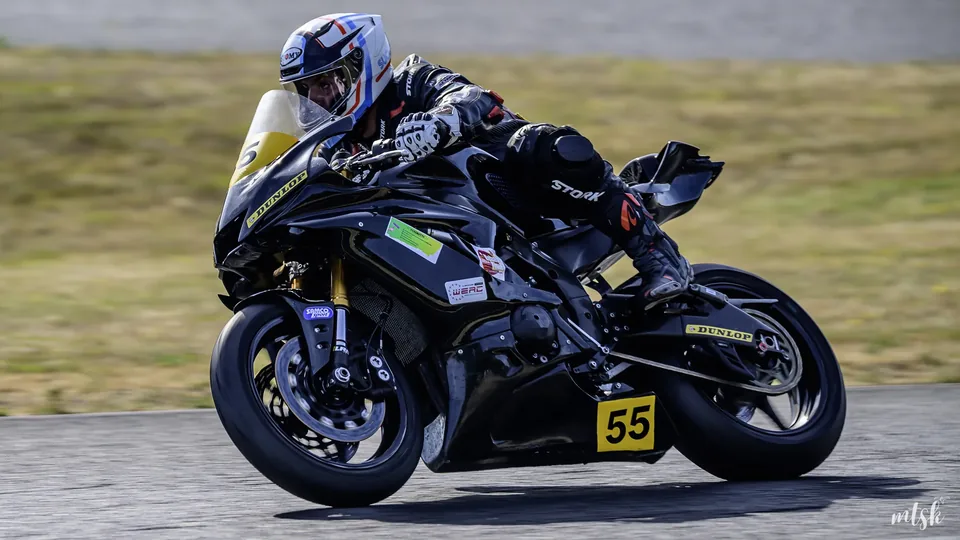 Moto noire portant le numéro 55 photographiée en virage