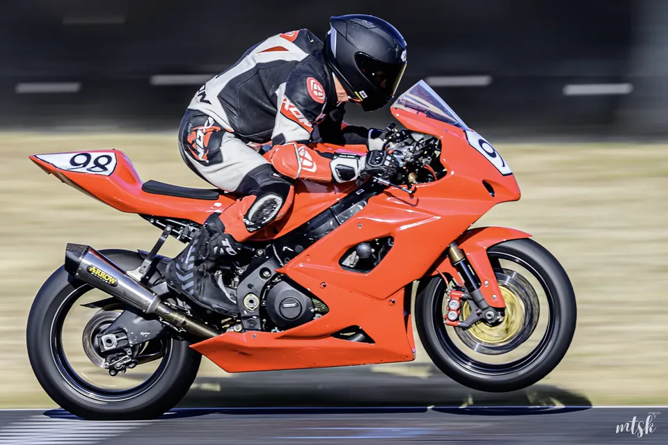 Moto orange au style classique photographiée de profil sur circuit