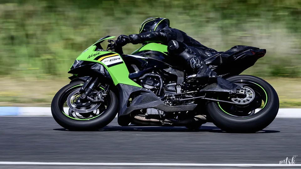 Moto verte en pleine accélération avec arrière-plan végétal flouté