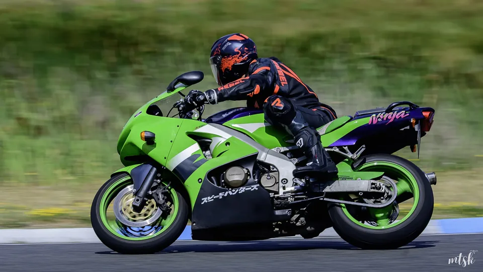 Moto verte en appui avec le pilote déhanché vers l’intérieur