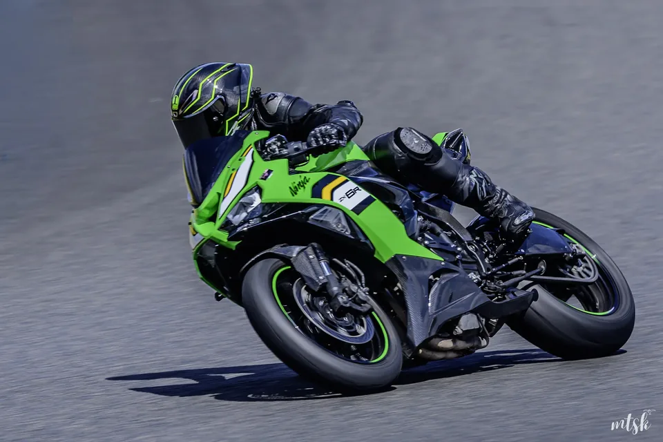 Moto verte fortement inclinée avec le genou du pilote au ras du bitume