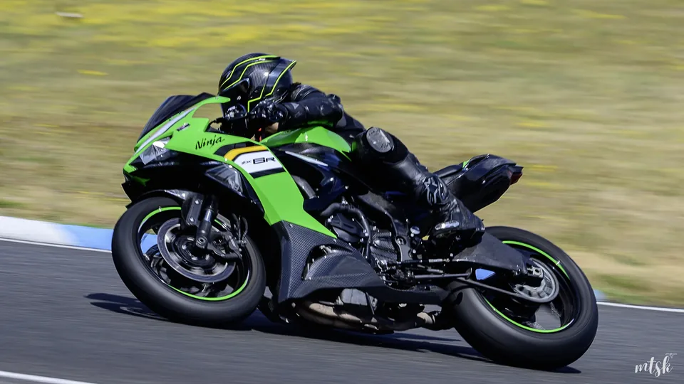 Moto verte photographiée de profil dans une courbe rapide