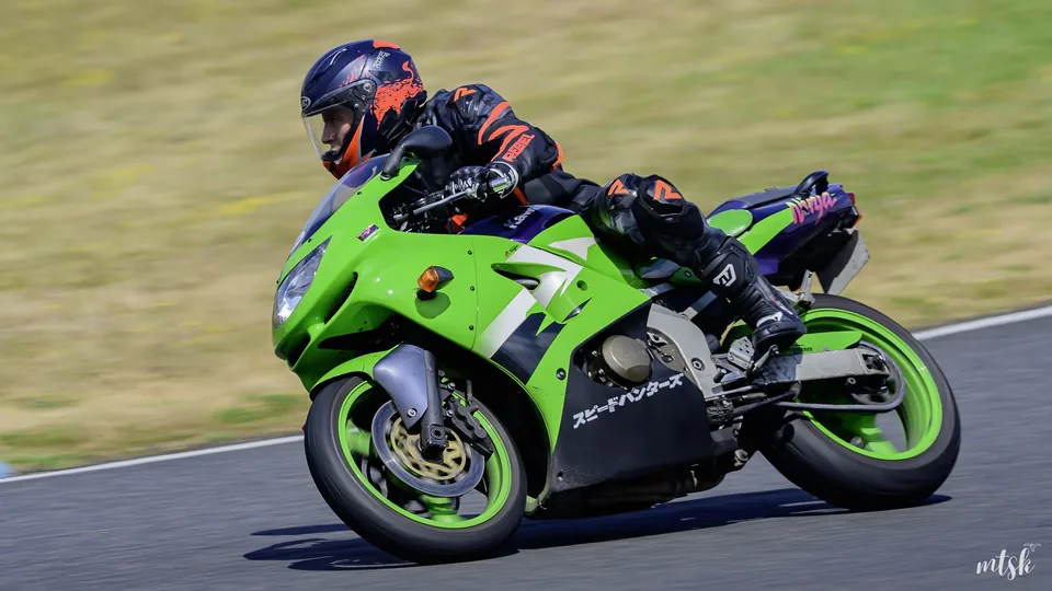 Moto verte relancée en sortie de courbe avec le pilote regroupé