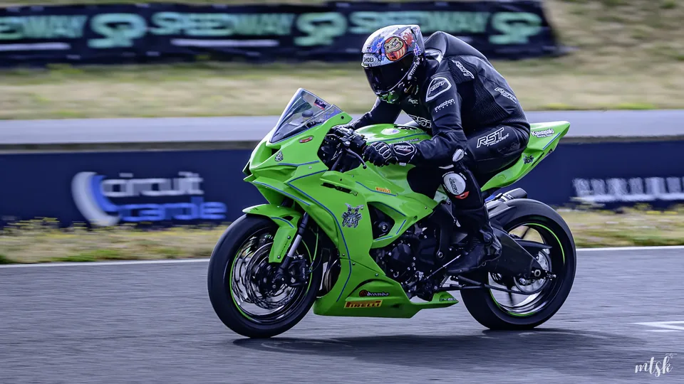 Moto verte en sortie de virage avec le pilote regroupé derrière la bulle