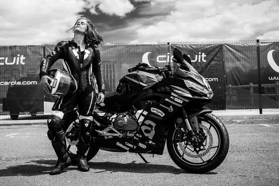 Pilote auprès de sa moto dans une scène de paddock en noir et blanc