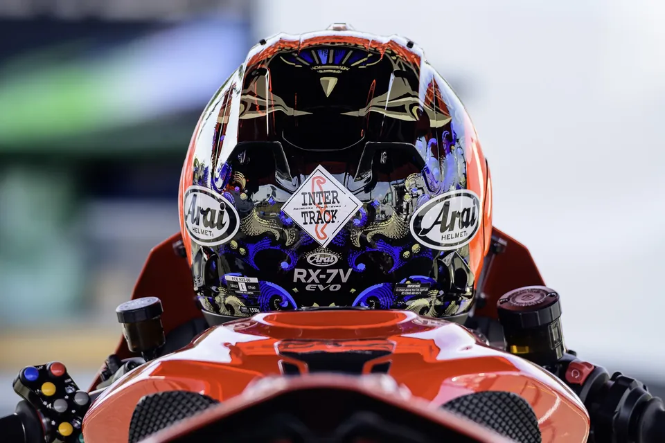 Pilote casqué vu de face derrière la bulle de sa moto de course