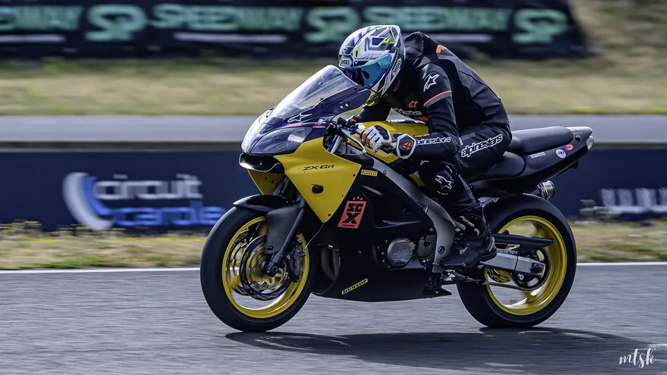 Pilote couché derrière la bulle d’une moto noire et jaune