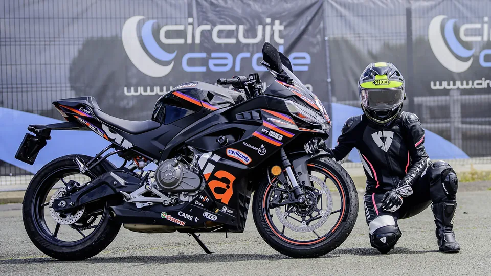 Pilote et membres du team déplaçant une moto dans le paddock