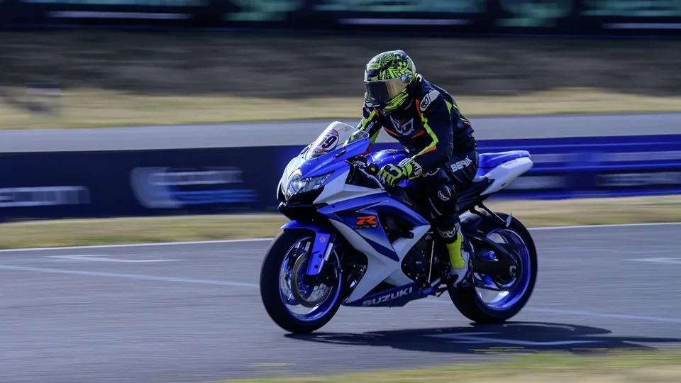 Pilote sur une moto bleue photographié de face sur le circuit