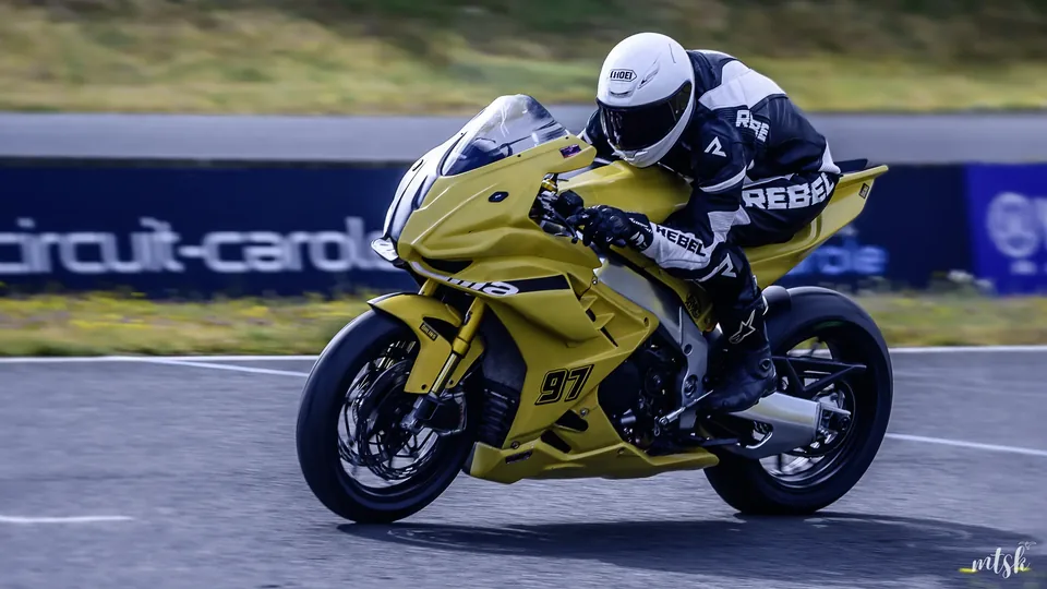 Pilote sur une moto jaune photographié en passage rapide sur la piste