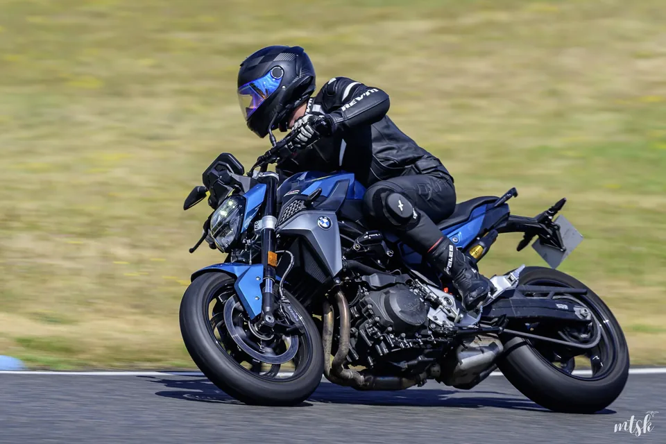 Pilote sur une moto sombre de type supermotard photographié de profil