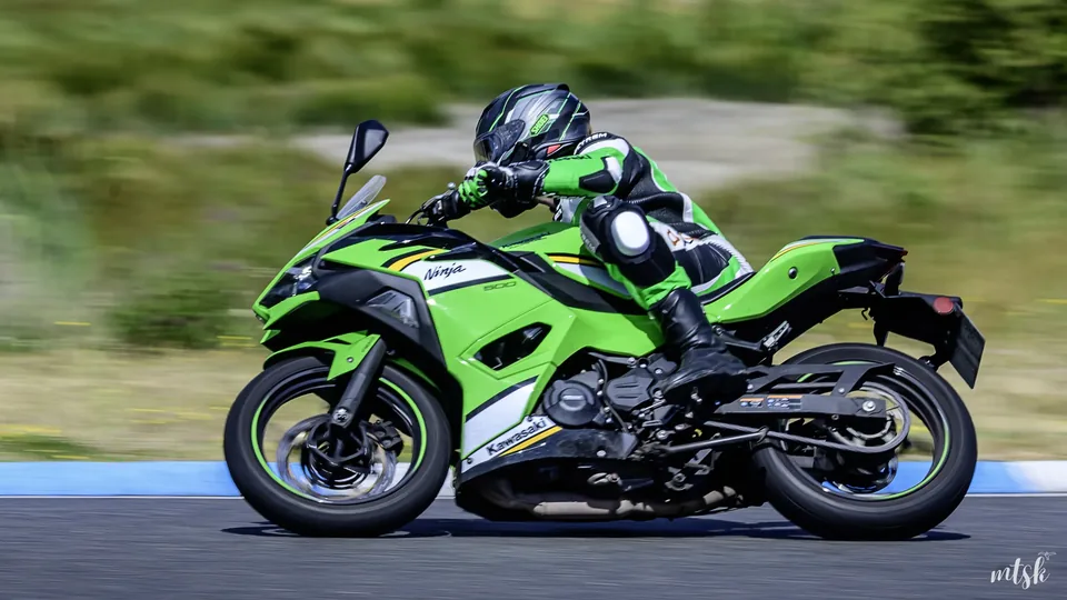Pilote sur une moto verte photographié en filé de profil