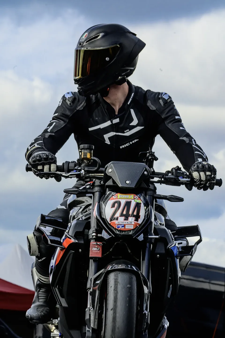 Portrait en pied d’un pilote moto équipé près de sa machine